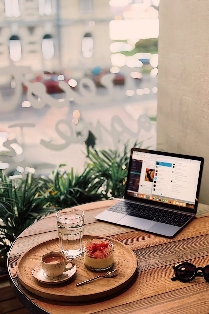 tray of fruits and coffee near laptop on table
