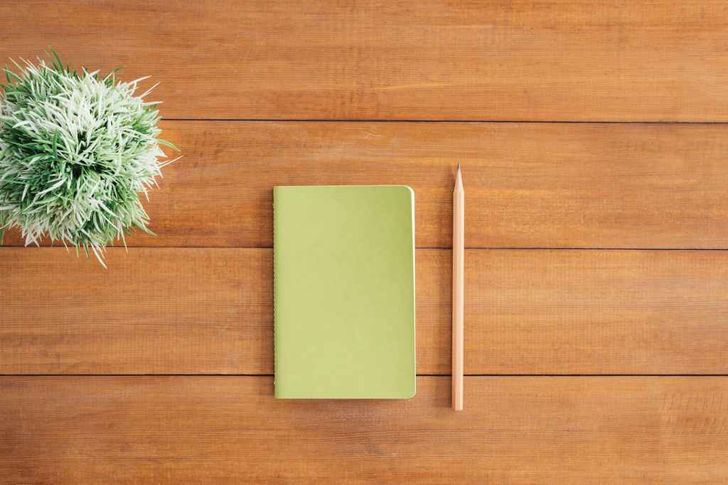 Green notes beside a pencil on brown wooden surface